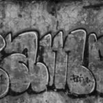 grayscale photo of concrete wall with graffiti