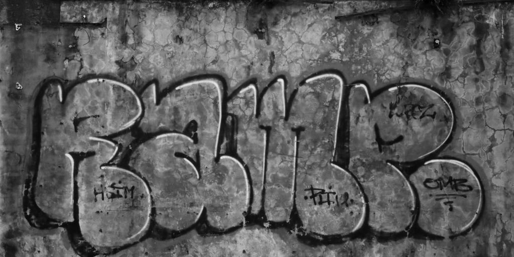 grayscale photo of concrete wall with graffiti