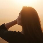 Woman looking thoughtfully towards a bright horizon.