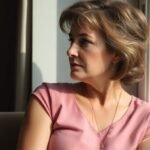Woman looking thoughtfully out a window on her birthday.