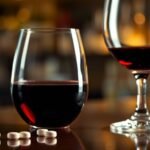 Cialis pill and wine glass with blurred bar background.